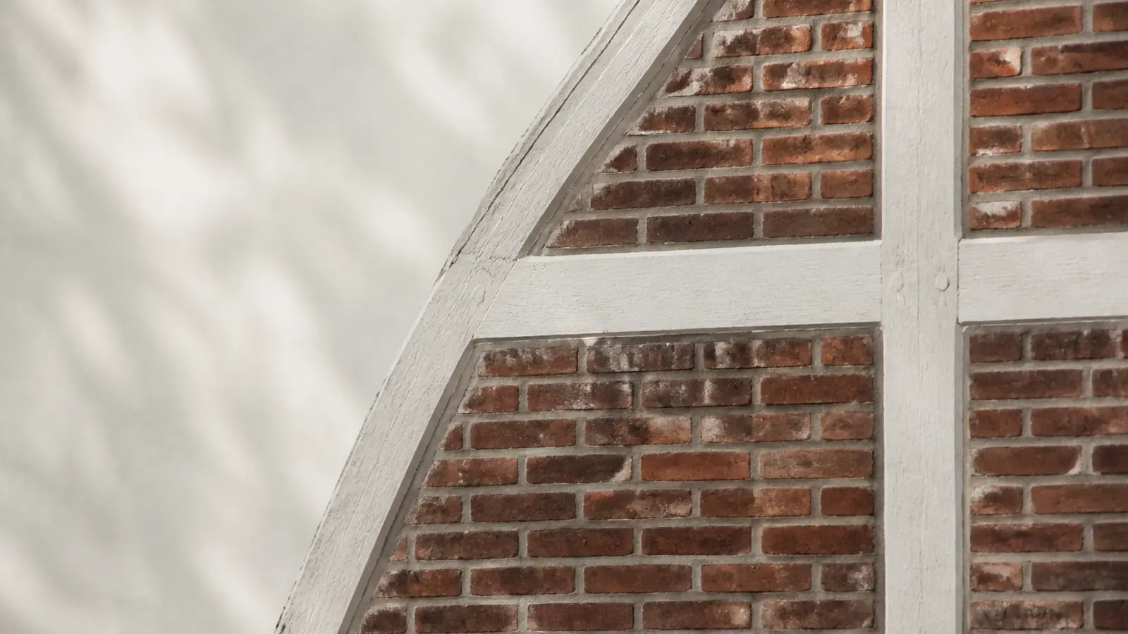 Detail einer norddeutschen Backsteinfassade mit wei&szlig; gefasstem Fachwerk im diffusen Tageslicht